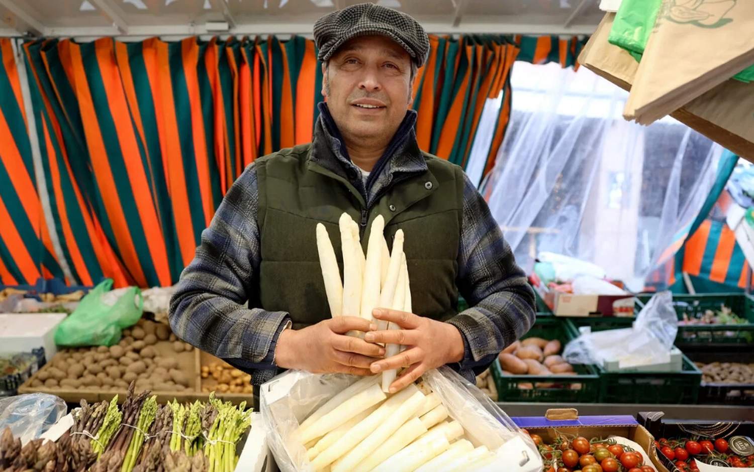 Marktstand mit orange-gr&uuml;n gestreifter Plane, Spargel in der Auslage